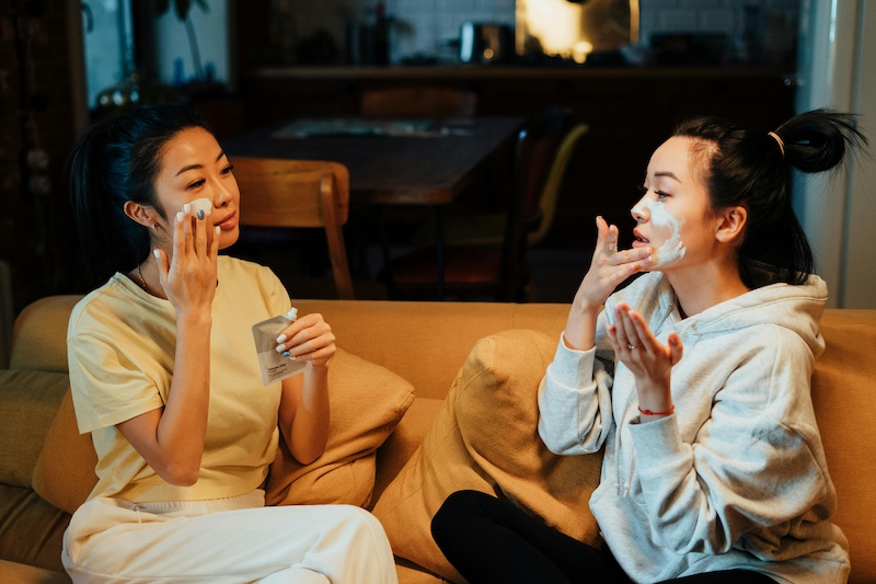 Two roommates in their apartment living room putting face masks on together